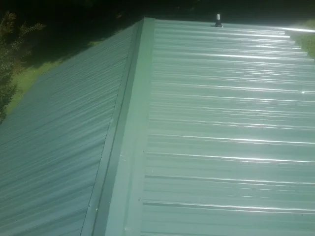 New green metal panels meeting at the ridge of a roof — Flat Roof Repair work by our crew in Union Springs