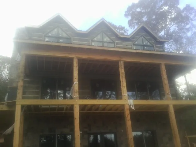 Dormers and porch framing on a large log home under construction — Roof Coating work by our crew in Union Springs