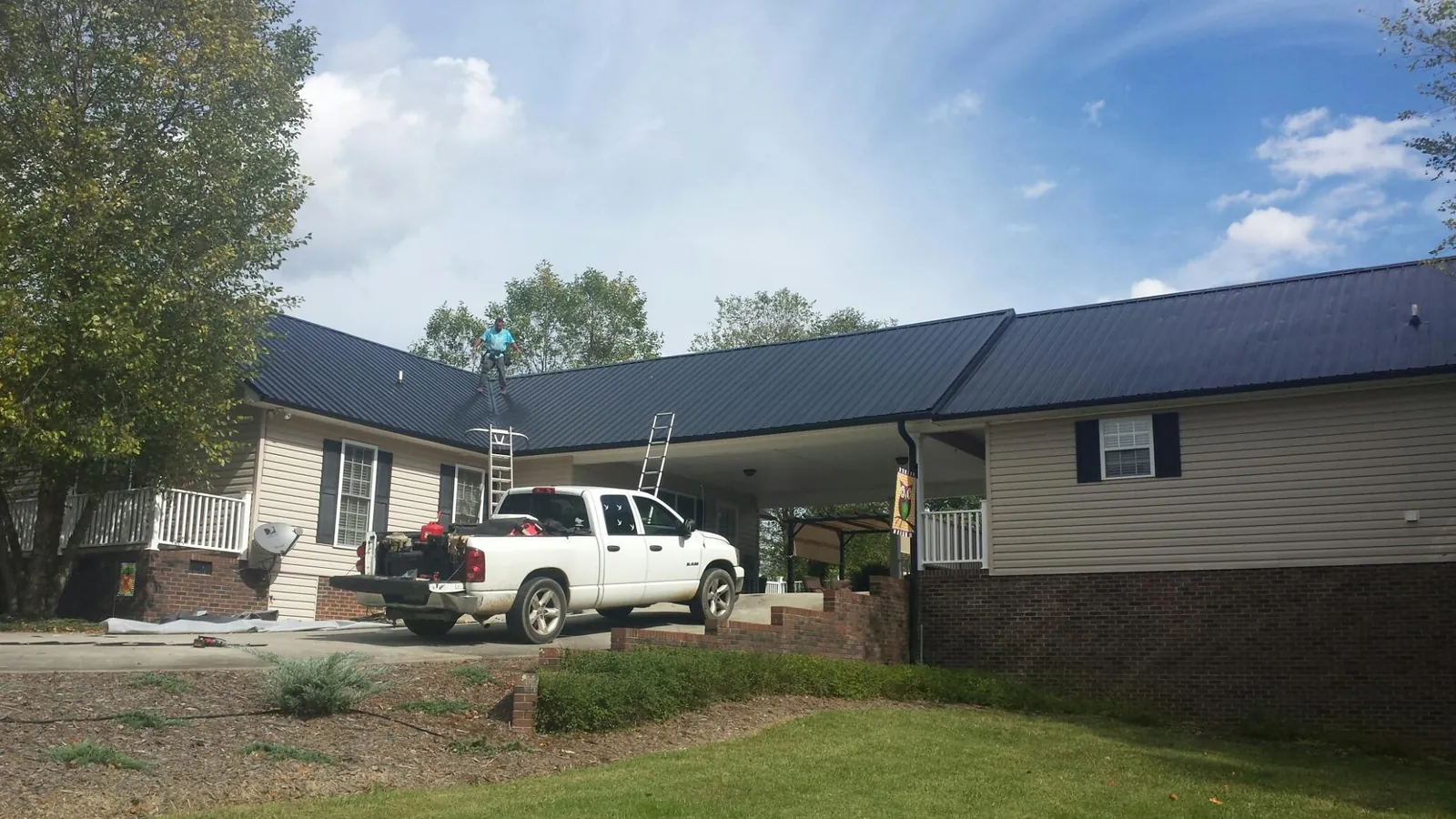 Black metal roof over a home and attached breezeway with ladders set in Union Springs
